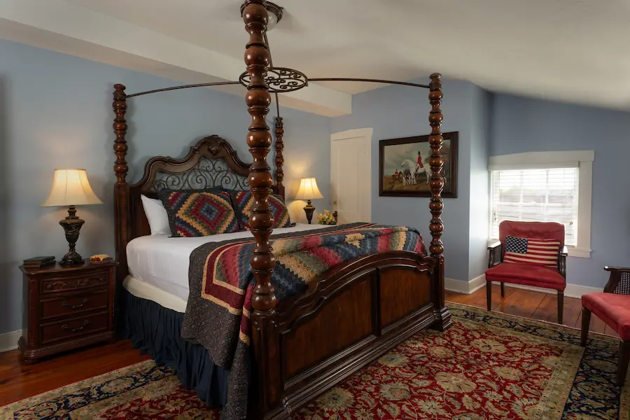 Bedroom with a four-poster bed, patterned bedding, and a red chair with an American flag design.